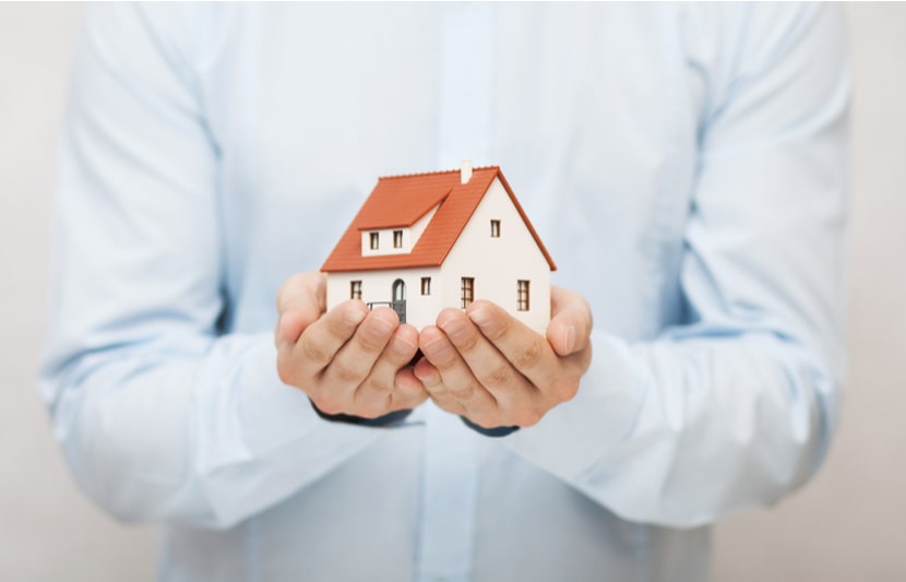 A person holds a model of a house