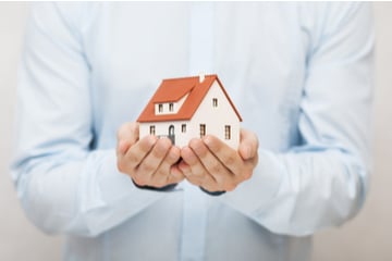 A person holding a model of a house