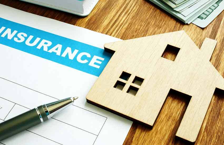 House-shaped paperweight holding down an insurance document on a wooden table