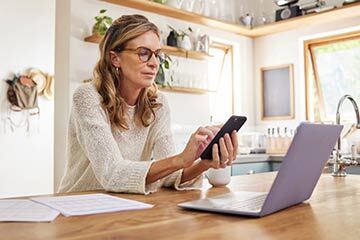 Woman typing on a mobile phone while sat at a desk