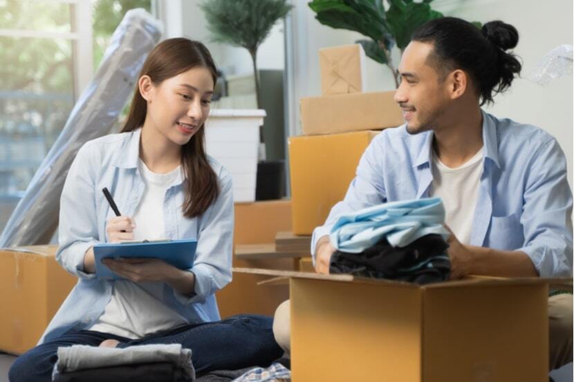 Young house-moving couple checking their list on a clipboard while packing