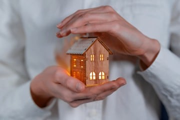 person cradling house in hands