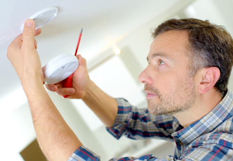 A landlord installing a smoke detector as part of his safety regulations 