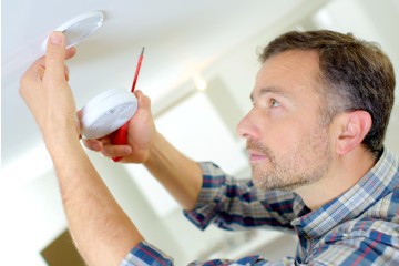 A landlord installing a smoke detector as part of his safety regulations 