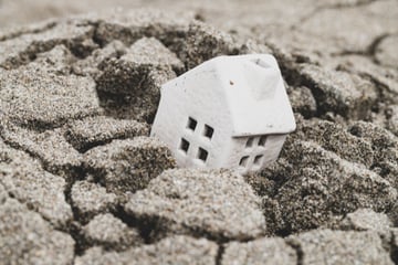 A model house sinks into sand