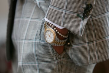 Rolex watch worn on the wrist of a man in a checked summer suit