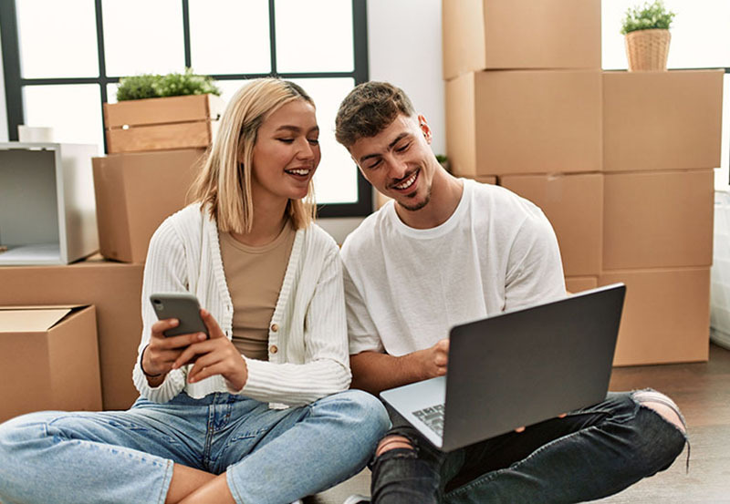 young couple on their laptop setting up broadband while moving house