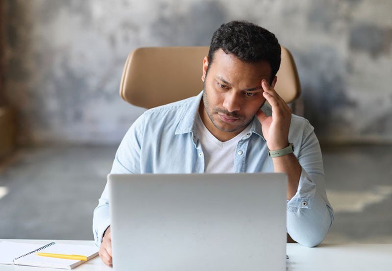 man looking concerned at his laptop during a broadband outage