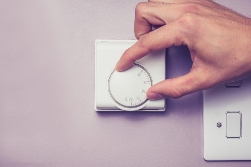 hand turning down thermostat