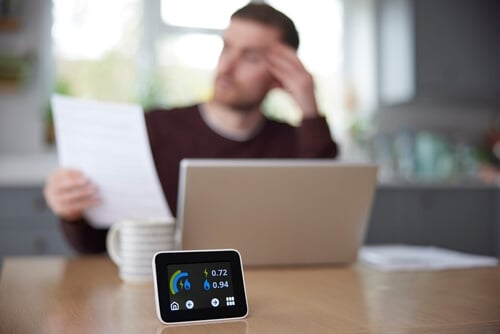 Man looking at energy bill with smart meter in foreground