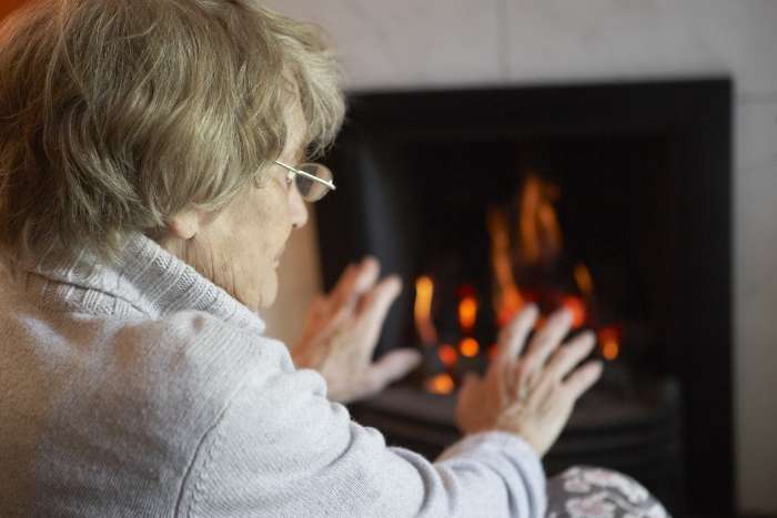 Older lady warming her hands by the fire