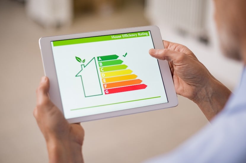 Hand holding digital tablet and looking at house energy efficiency rating