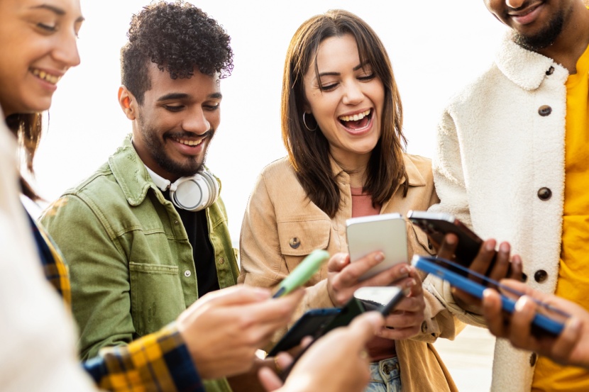 happy group of young friends using smartphone