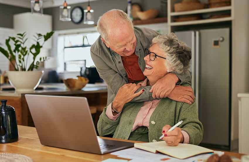 Smiling elderly couple sitting together at a table, reviewing documents related to their cash value life insurance policy