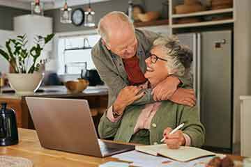 Smiling elderly couple sitting together at a table, reviewing documents related to their cash value life insurance policy