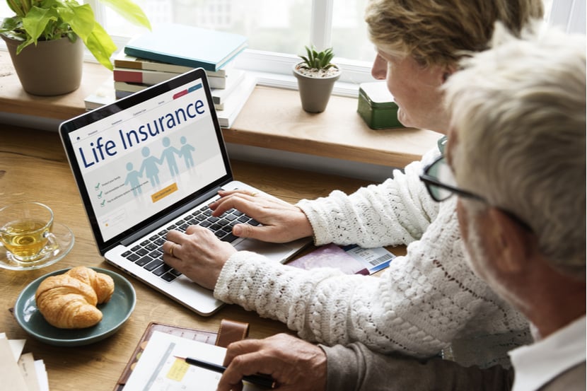 An elderly couple look at changing life insurance on their laptop