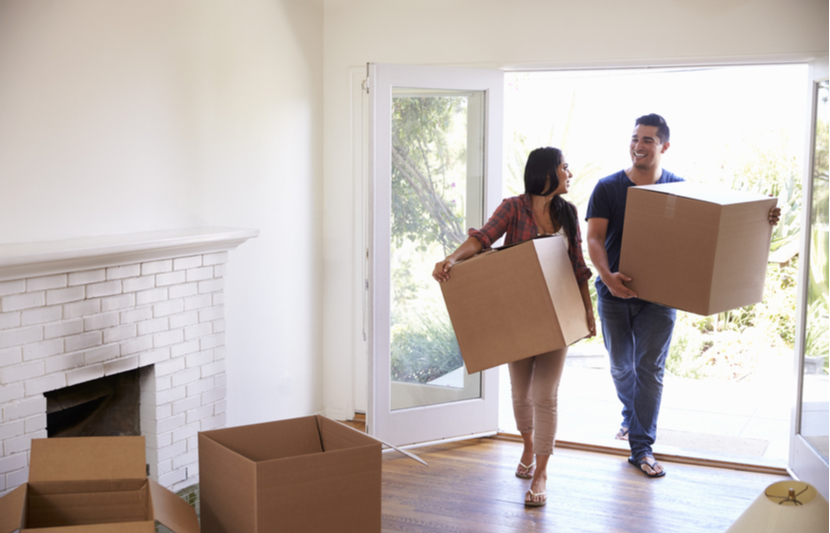 A couple with moving boxes walk into their new home