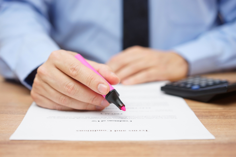 A person holds a highlighter above a document