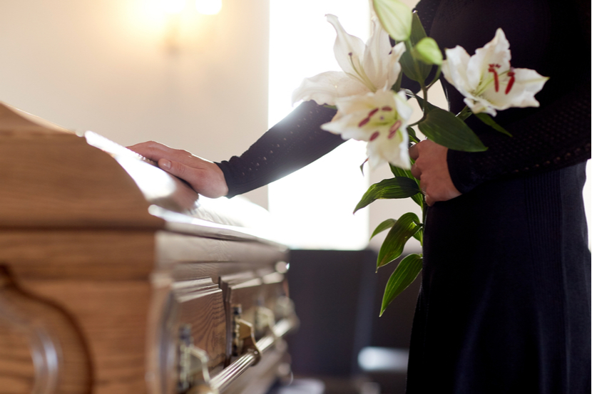 A mourner touches a coffin during a funeral