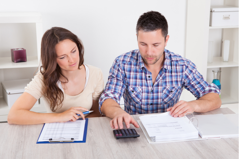 A couple with forms on a table as they try to work out their life insurance costs