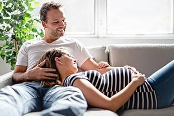 A man and woman relax together on a couch, enjoying each other's company in a cozy setting.