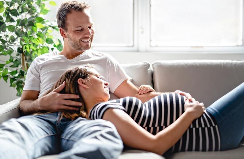A man and woman relax together on a couch, enjoying each other's company in a cozy setting.