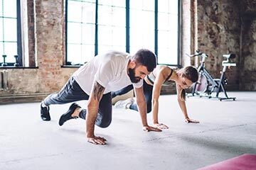 A man and woman performing push-ups side by side in a gym, focused on their workout routine.