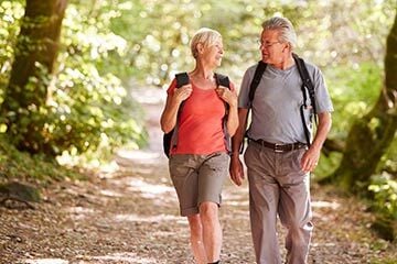 An over 60 couple walking in the woods discussing life insurance