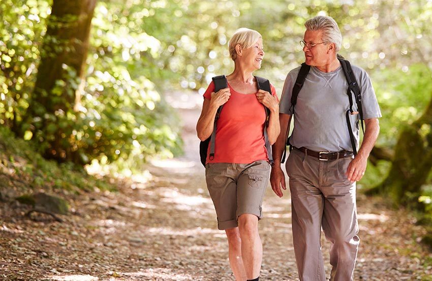 An over 60 couple walking in the woods discussing life insurance