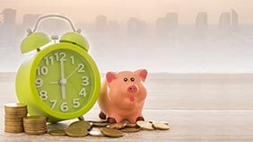 Piggy bank and clock on a pile of coins