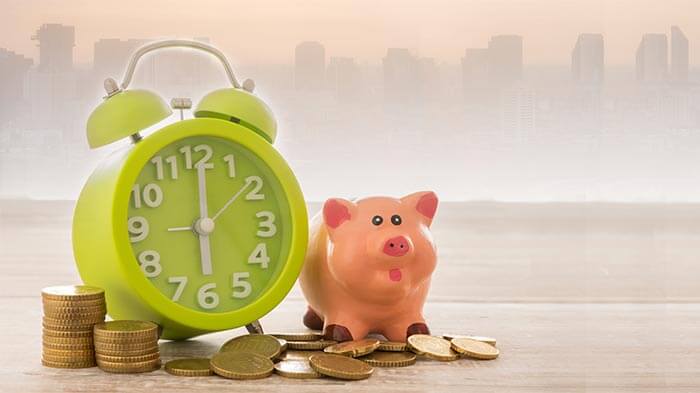 Piggy bank and clock on a pile of coins