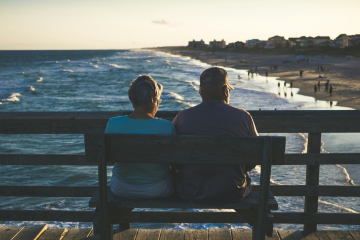 Elderly couple sat on a bench at the beach