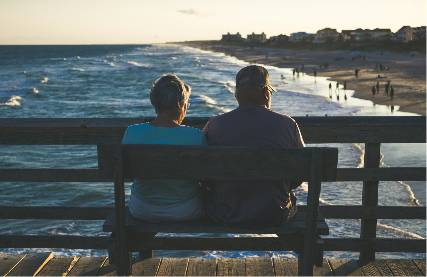 Elderly couple sat on a bench at the beach