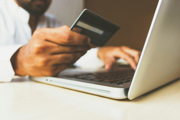 Man using laptop and holding a credit card 