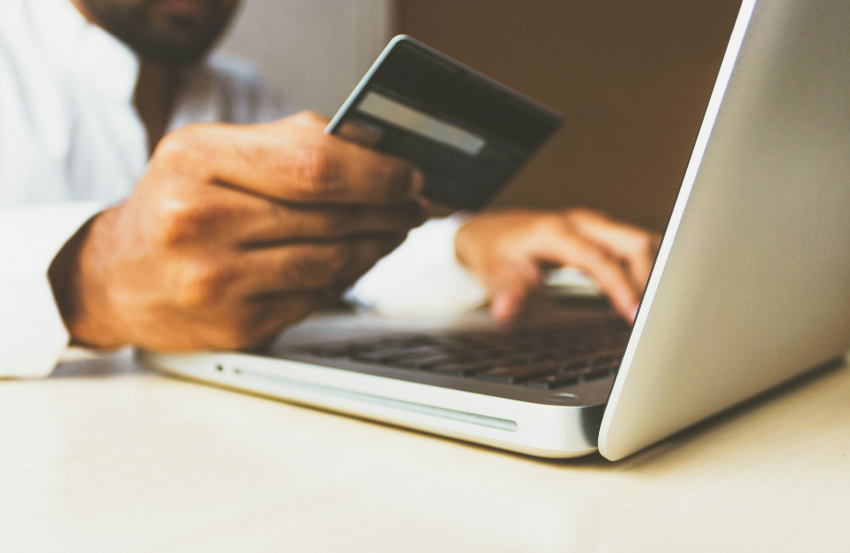 Man using laptop and holding a credit card 