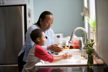 Boy and female family member at a sink washing hands 