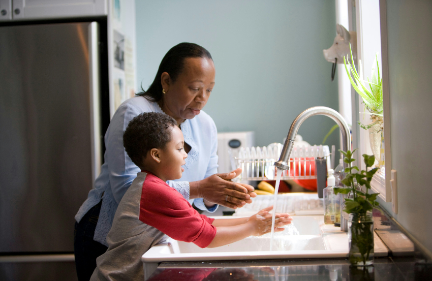 Boy and female family member at a sink washing hands 