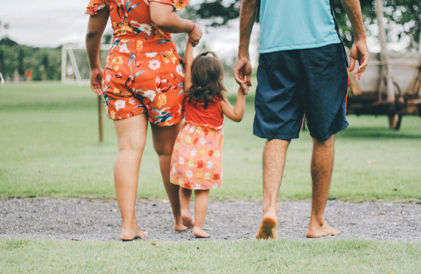 image showing the back of a family walking together inthe summer 