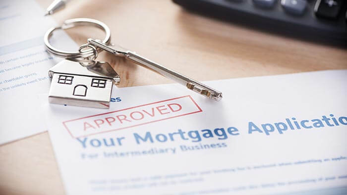 An approved mortgage application with a set of house keys in the foreground