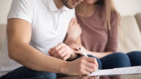 Two people signing documents for a house