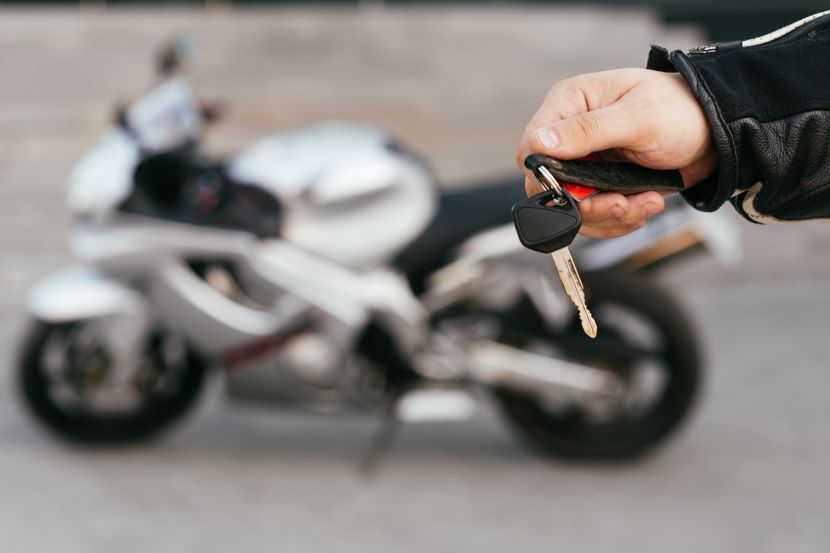 Hand holding keys with motorbike in background
