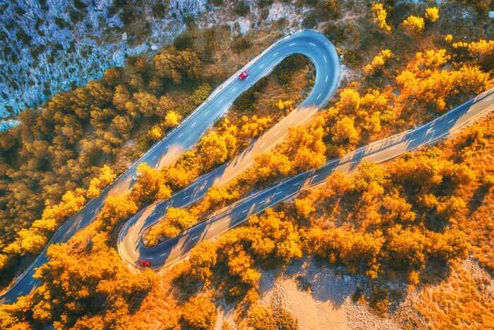 An overhead view of a car driving along a winding road
