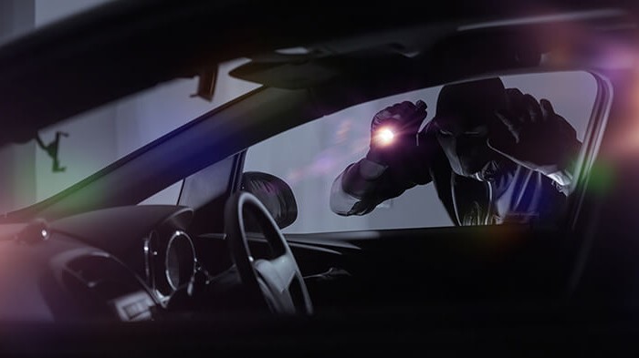 Robber looking into a car with torch