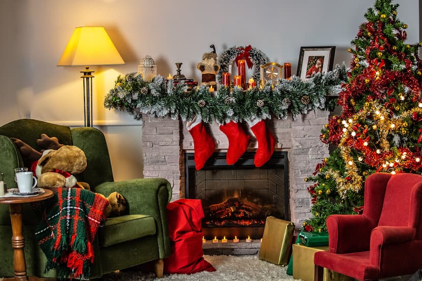 A living room decorated for Christmas with a Christmas tree, stockings on the fireplace and presents