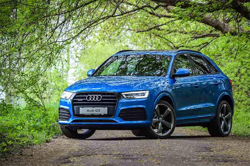 Royal blue Audi Q3 parked in green forestry