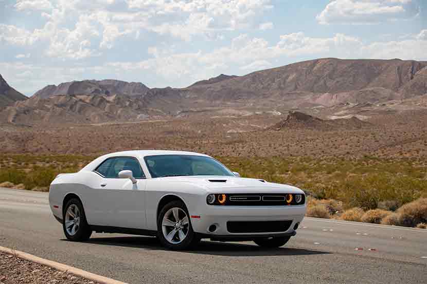 White Dodge Challenger with mountain desert landscape in background