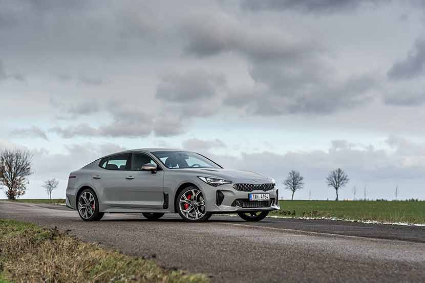 Grey Kia Stinger parked in countryside field