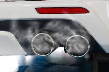 Double car exhaust pipes on white car with exhaust gases coming out