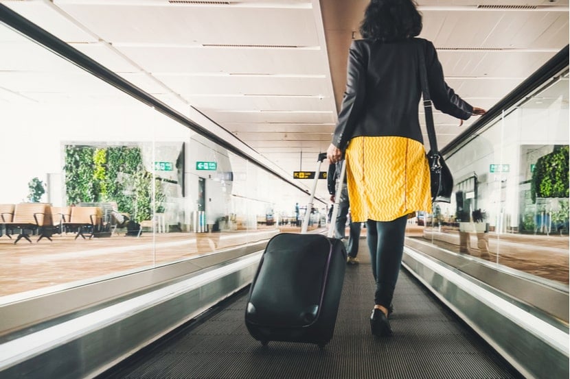 A woman carries a suitcase in an airport