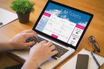A traveller books last minute flights on their laptop